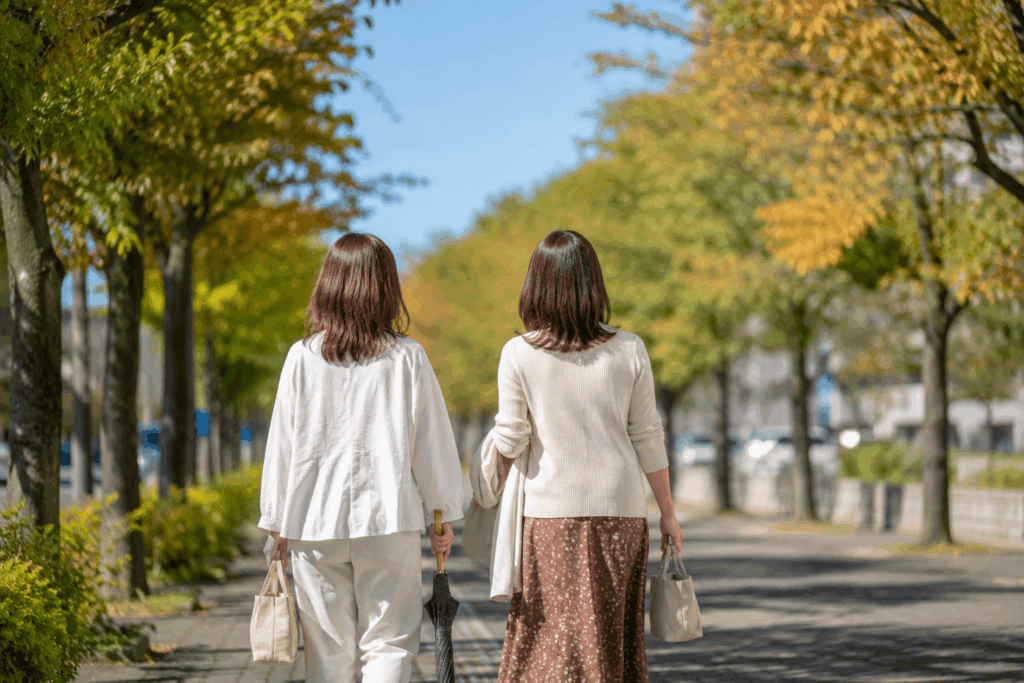 秋の街並みを歩く女性カップルの後ろ姿、9月下旬の爽やかな散歩イメージ