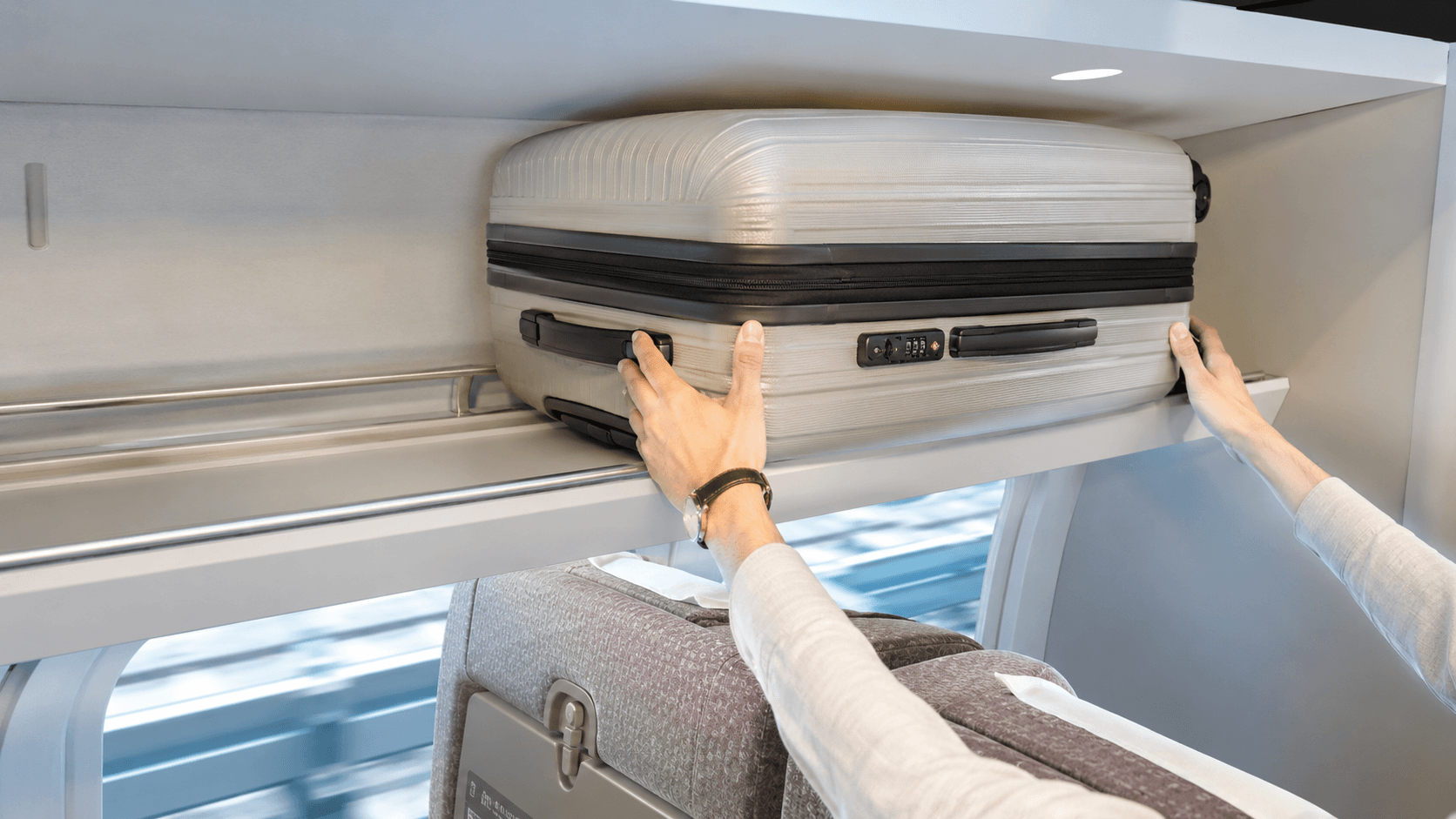 A large suitcase placed in the oversized baggage area behind a Shinkansen seat