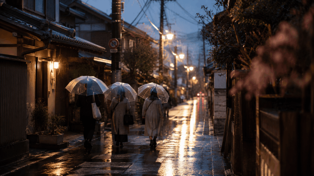 雨上がりの街並みを傘をさして歩く人々の後ろ姿