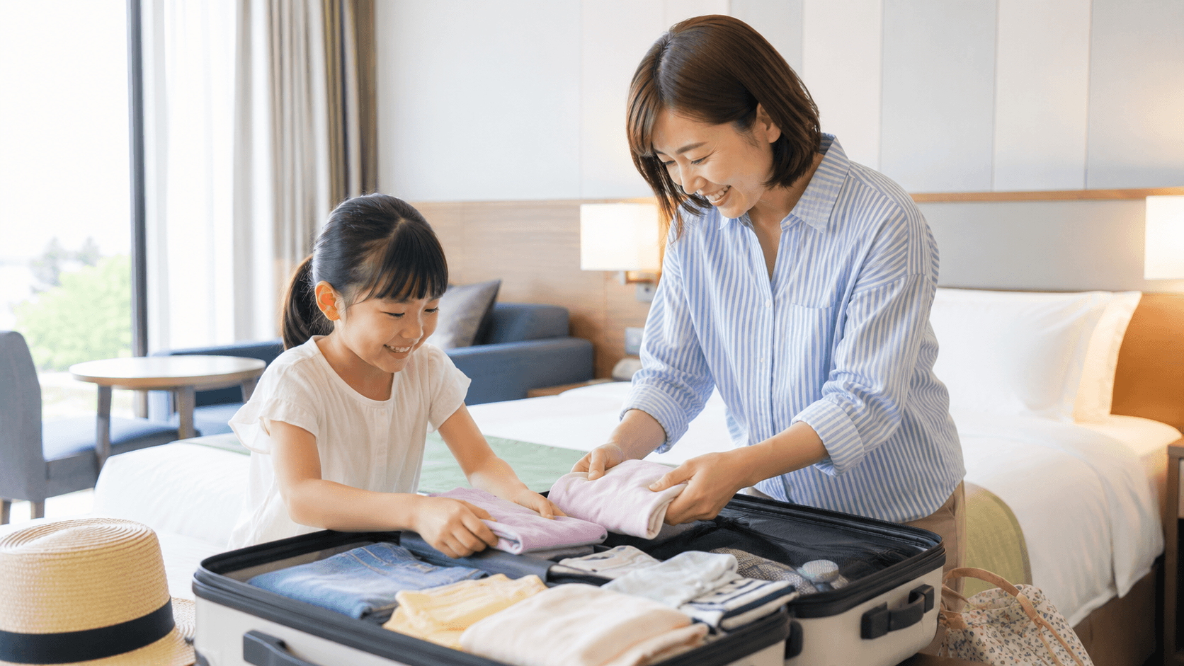 ホテルの部屋で旅行の荷物を整理する親子のイメージ