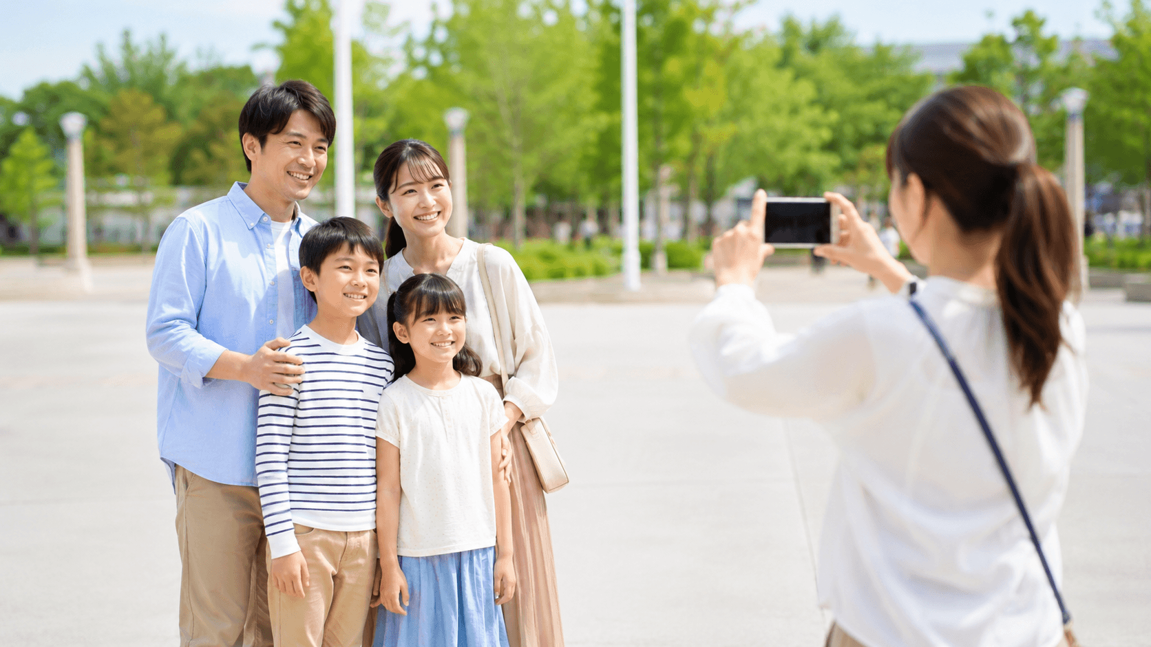 テーマパークで記念写真を撮る家族のイメージ