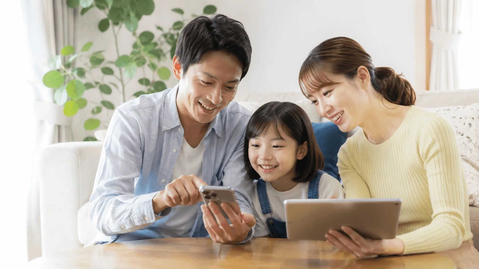 家族でテーマパークのチケットをスマホで予約しているイメージ