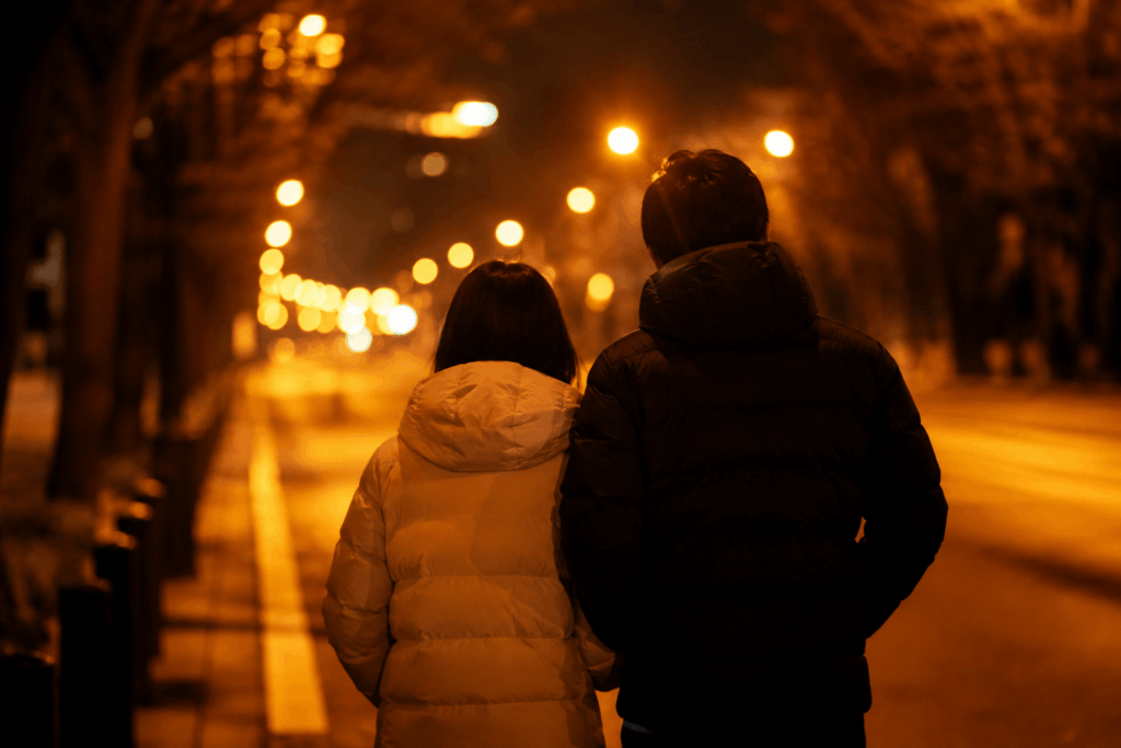 ダウンジャケット姿で冬の夜の街を並んで歩く二人の後ろ姿