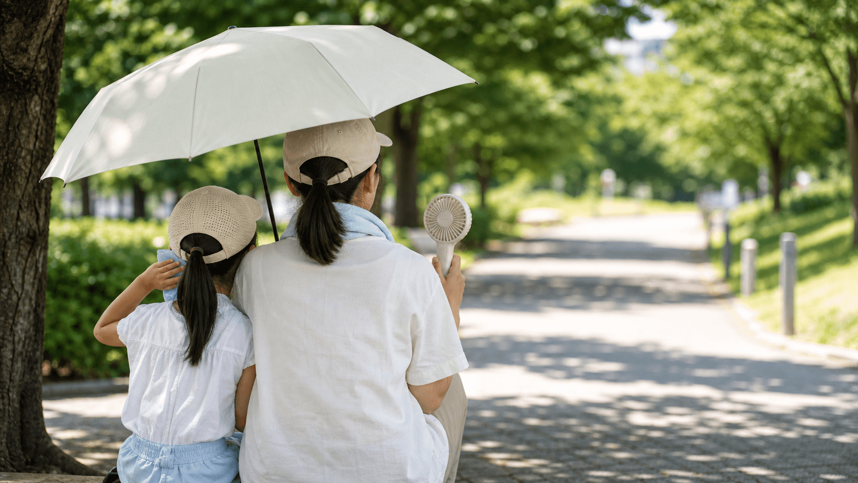 日傘と冷却グッズで暑さ対策をする親子のイメージ
