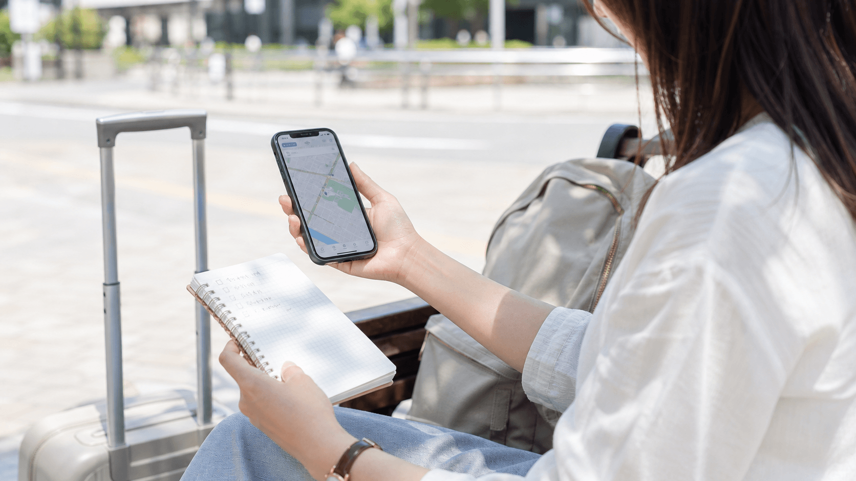 2つのパークを行き来する予定をスマートフォンで確認する旅行者のイメージ