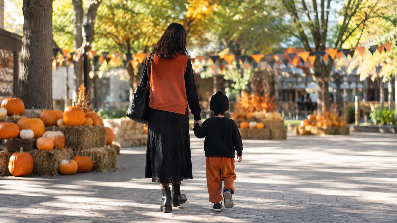 ハロウィンらしいオレンジと黒を取り入れた秋の服装で歩く親子の後ろ姿