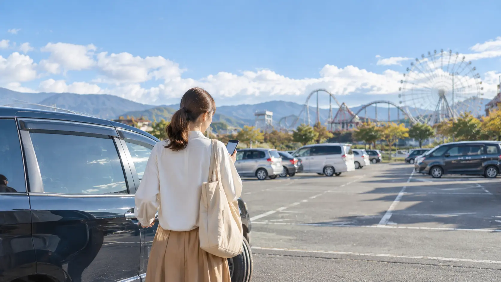 車の助手席でスマートフォンを見ながら到着前の予定を立てている手元